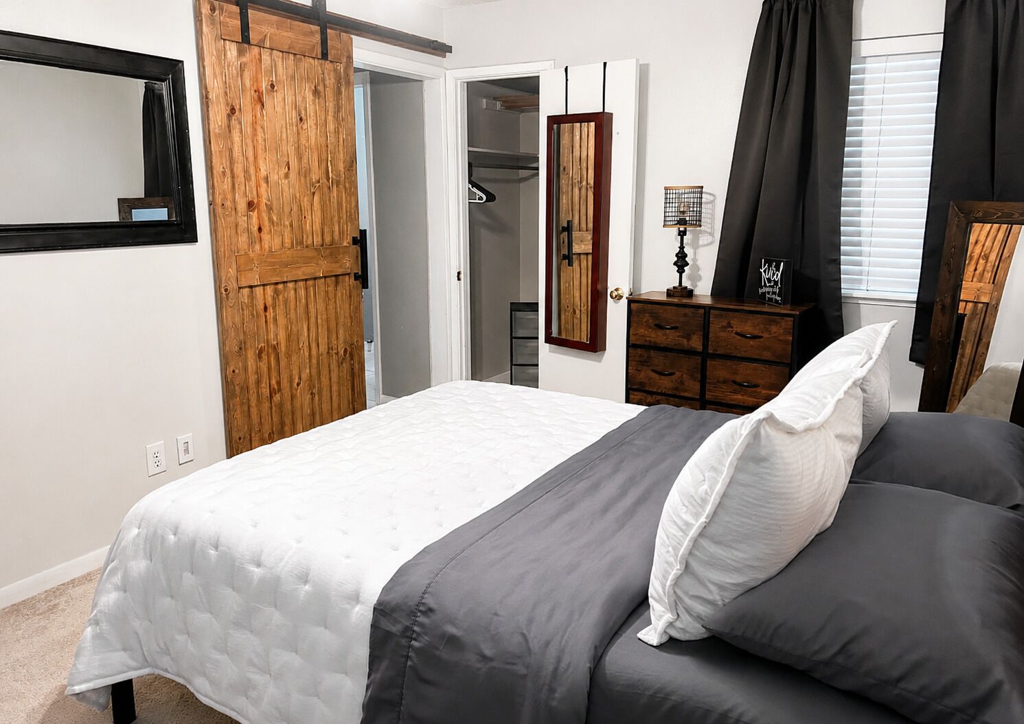 A bedroom with a bed, a wardrobe, a mirror, and a dresser.