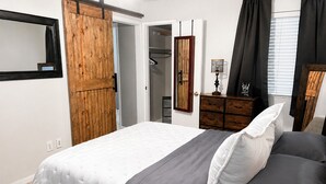 Un dormitorio con cama, armario, espejo y cómoda.