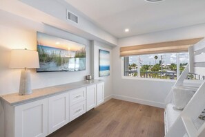 A modern kitchen with a large window, white cabinetry, and artwork on the wall. - Martinique South 207 (Holmes Beach)