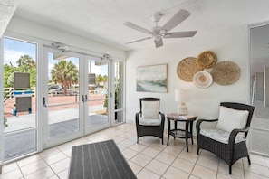 A room with a ceiling fan, wicker chairs, a table with a lamp, and a view through glass doors. - Martinique South 207 (Holmes Beach)
