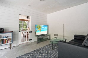 A living room with a television, a glass coffee table, a sofa, and a bookshelf. - Manatee Harbor (Anna Maria)