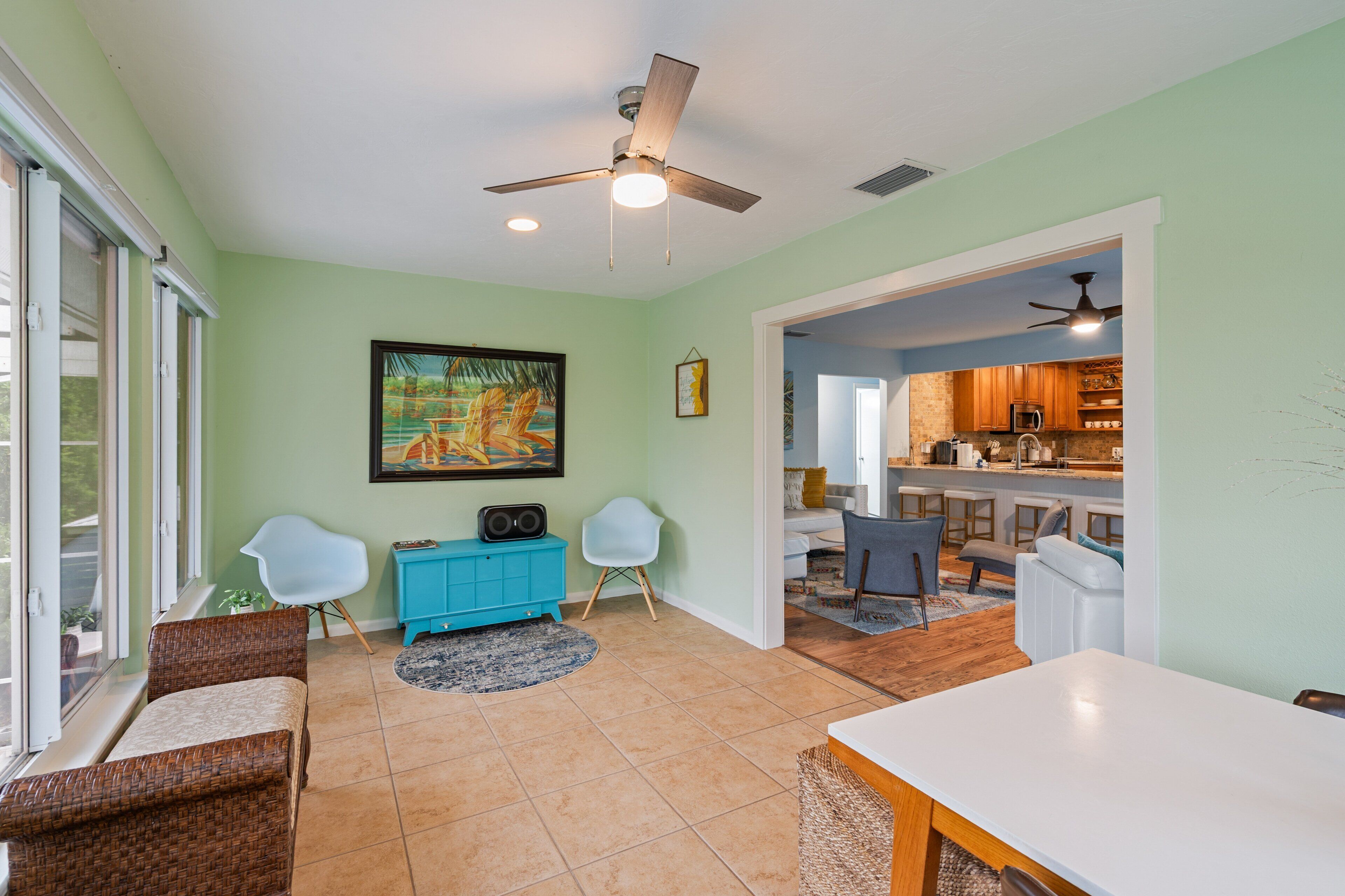 A spacious living area with a dining table, chairs, a blue cabinet, and a ceiling fan.