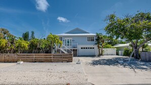A single-story house with a covered garage, a gravel driveway, and a wooden fence. - Canal Front, Manatee Harbor by SeaBreeze Vacation (Anna Maria)