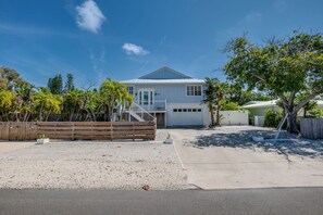 A single-story house with a covered garage, a gravel driveway, and a wooden fence. - Canal Front, Manatee Harbor by SeaBreeze Vacation (Anna Maria)