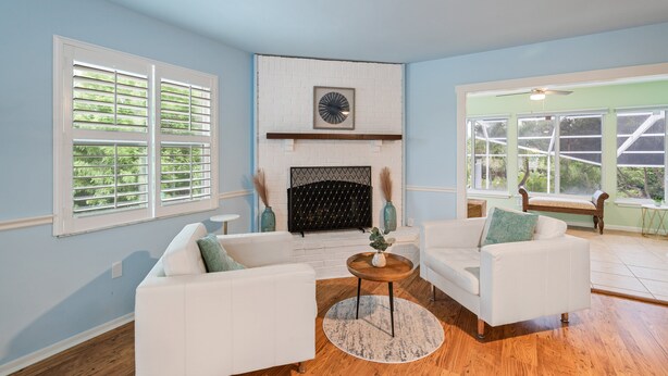 A living room with two white sofas, a fireplace, and large windows. - Canal Front, Manatee Harbor by SeaBreeze Vacation (Anna Maria)