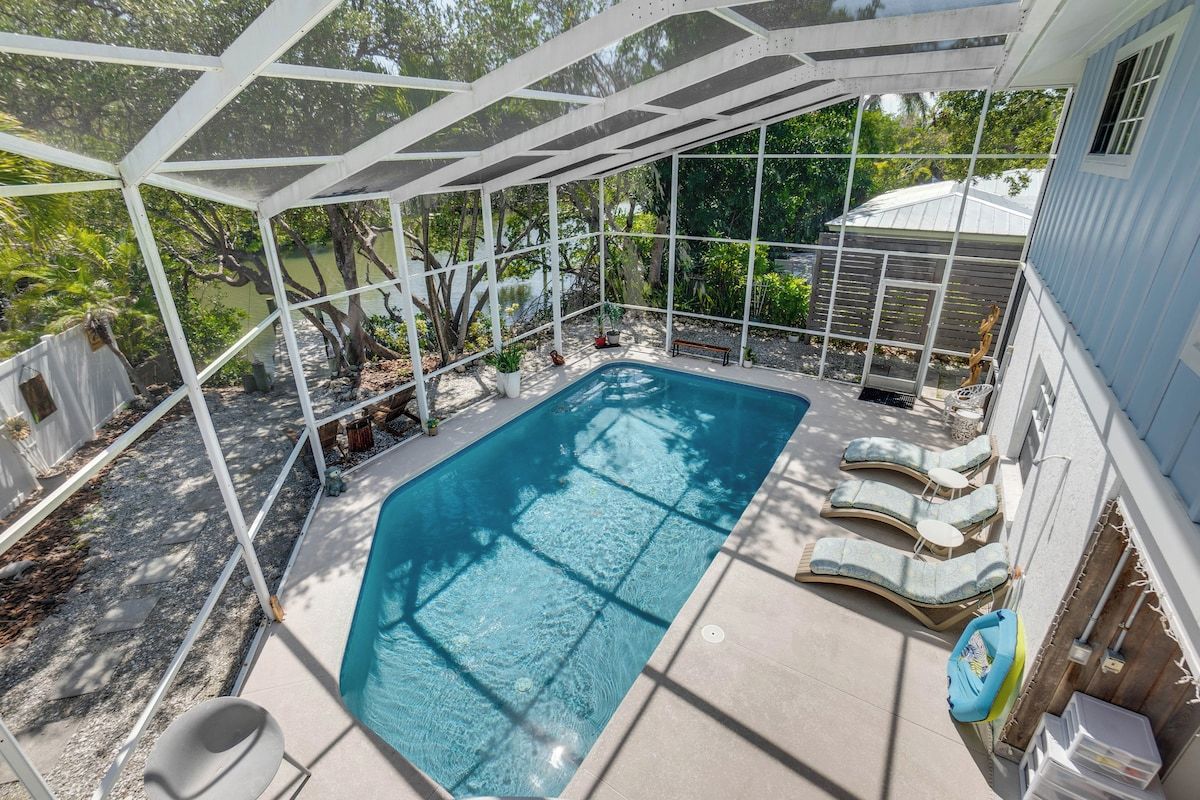 A covered swimming pool with lounge chairs and a pergola structure.