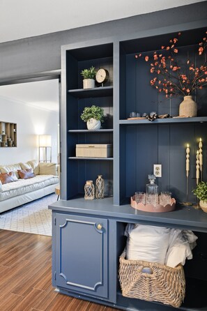 Ein Wohnzimmer mit einer dunkelblauen Unterhaltungseinheit, einem weißen Sofa und einem Holzboden.