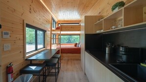 Een kleine keuken met houten wanden, een zithoek met banken en een raam dat voor natuurlijk licht zorgt.