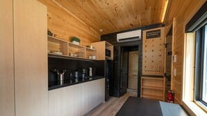 Een compacte keuken met houten kastjes, een zwart aanrecht en een inbouwfornuis.