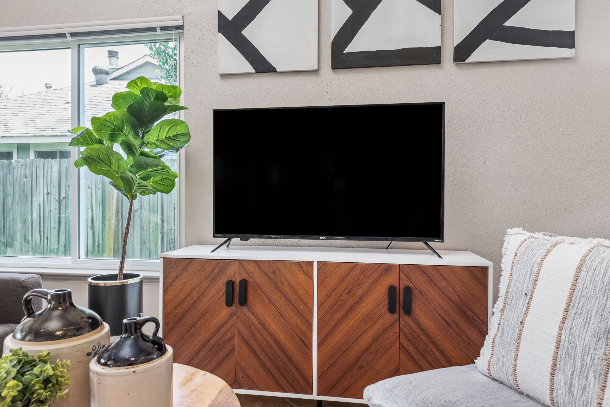A living room with a TV on a wooden cabinet, a plant, and a couch.