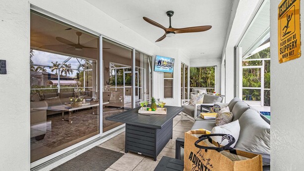 A spacious patio with a dining area, sliding glass doors, and a ceiling fan. - Waterfront Gulf Access Retreat with Heated Pool, Dock & Outdoor Fun - Villa Snowscape - Roelens (Cape Coral)