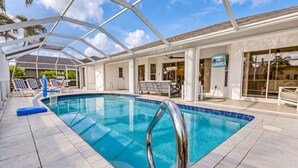 A swimming pool with a glass enclosure, lounge chairs, and a view of the sky. - Waterfront Gulf Access Retreat with Heated Pool, Dock & Outdoor Fun - Villa Snowscape - Roelens (Cape Coral)