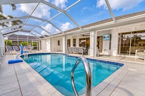 A swimming pool with a glass enclosure, lounge chairs, and a view of the sky. - Waterfront Gulf Access Retreat with Heated Pool, Dock & Outdoor Fun - Villa Snowscape - Roelens (Cape Coral)