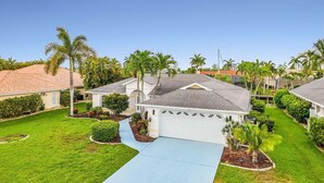 A residential neighborhood with houses, palm trees, and a well-maintained lawn. - Waterfront Gulf Access Retreat with Heated Pool, Dock & Outdoor Fun - Villa Snowscape - Roelens (Cape Coral)