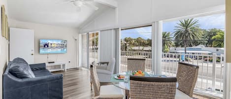A spacious balcony with wicker furniture, a flat-screen TV, and a view of the street.