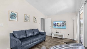 A modern living room with a leather sofa, a television, and framed artwork on the wall. - Plunge into Fun & Sun at Siesta Key- A Coastal Gem - Aloha Kai Suite - Roelens (Sarasota)