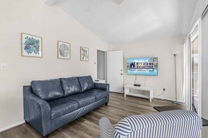Ein modernes Wohnzimmer mit einem Ledersofa, einem Fernseher und gerahmten Kunstwerken an der Wand.