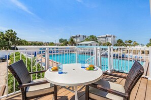 Ein Balkon mit Pool, Korbstühlen und einem Tisch mit Speisen und Getränken.