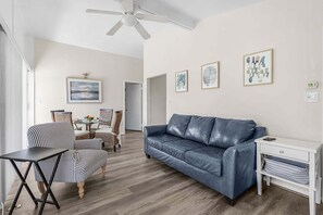 Ein Wohnzimmer mit einer Ledersofa, einem Essbereich mit Korbstühlen und einem Deckenventilator.