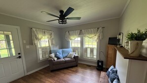 A room with a ceiling fan, a brown leather sofa, and a wooden floor.