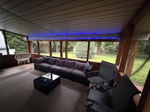 A covered outdoor seating area with a sofa, chairs, and a coffee table.