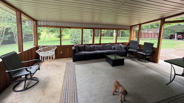 A covered outdoor seating area with a sectional sofa, chairs, and a hanging chair.