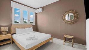 Une chambre à coucher avec un lit, une table de chevet et un petit tabouret.