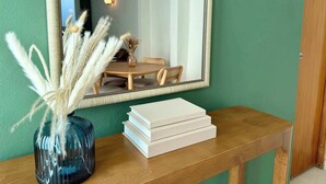 Une console en bois surmontée d’un vase rempli de plumes d’herbe des pampas et d’une pile de livres.