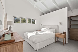 A bedroom with a bed, bedside table, lamp, and a window. - Curly’s Beach House (Gold Coast)