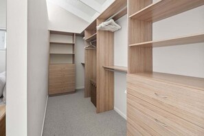 Ein begehbarer Kleiderschrank mit Holzböden, Schubladen, einer Kleiderstange und einem Teppichboden.