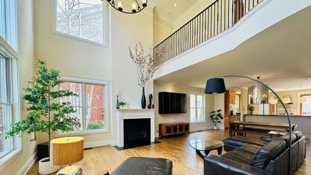 Un amplio salón con chimenea, un sofá grande, un comedor y una escalera que sube a un nivel superior.
