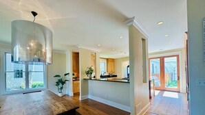 Una cocina amplia con pisos de madera, una isla grande y una lámpara colgante moderna.
