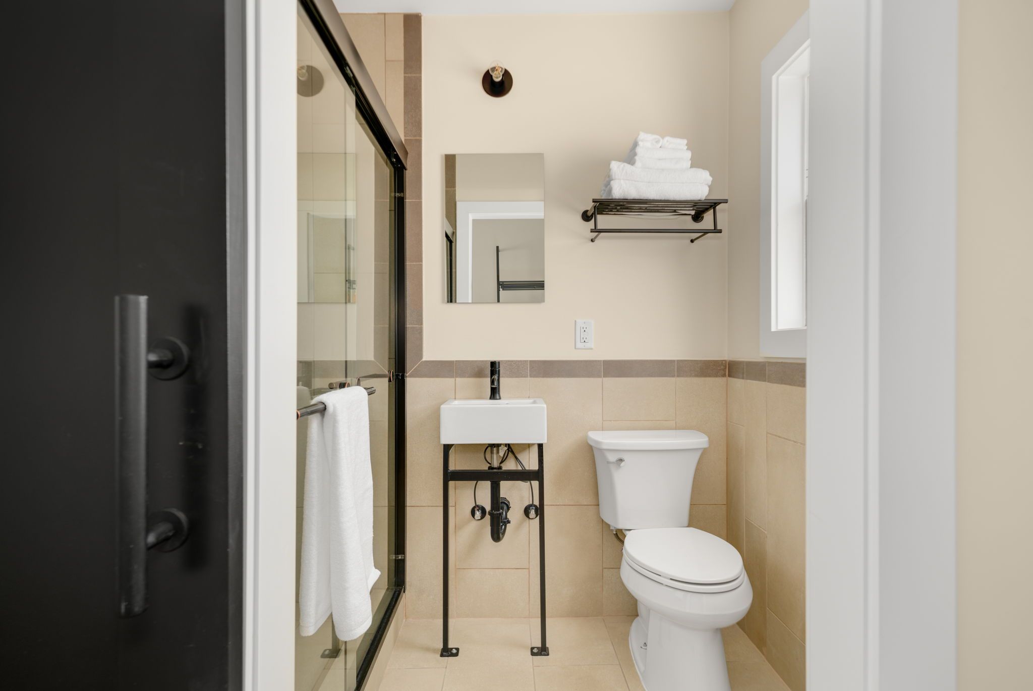 A bathroom with a toilet, sink, and glass shower enclosure.