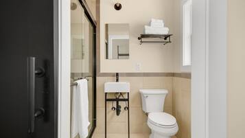A bathroom with a toilet, sink, and glass shower enclosure.