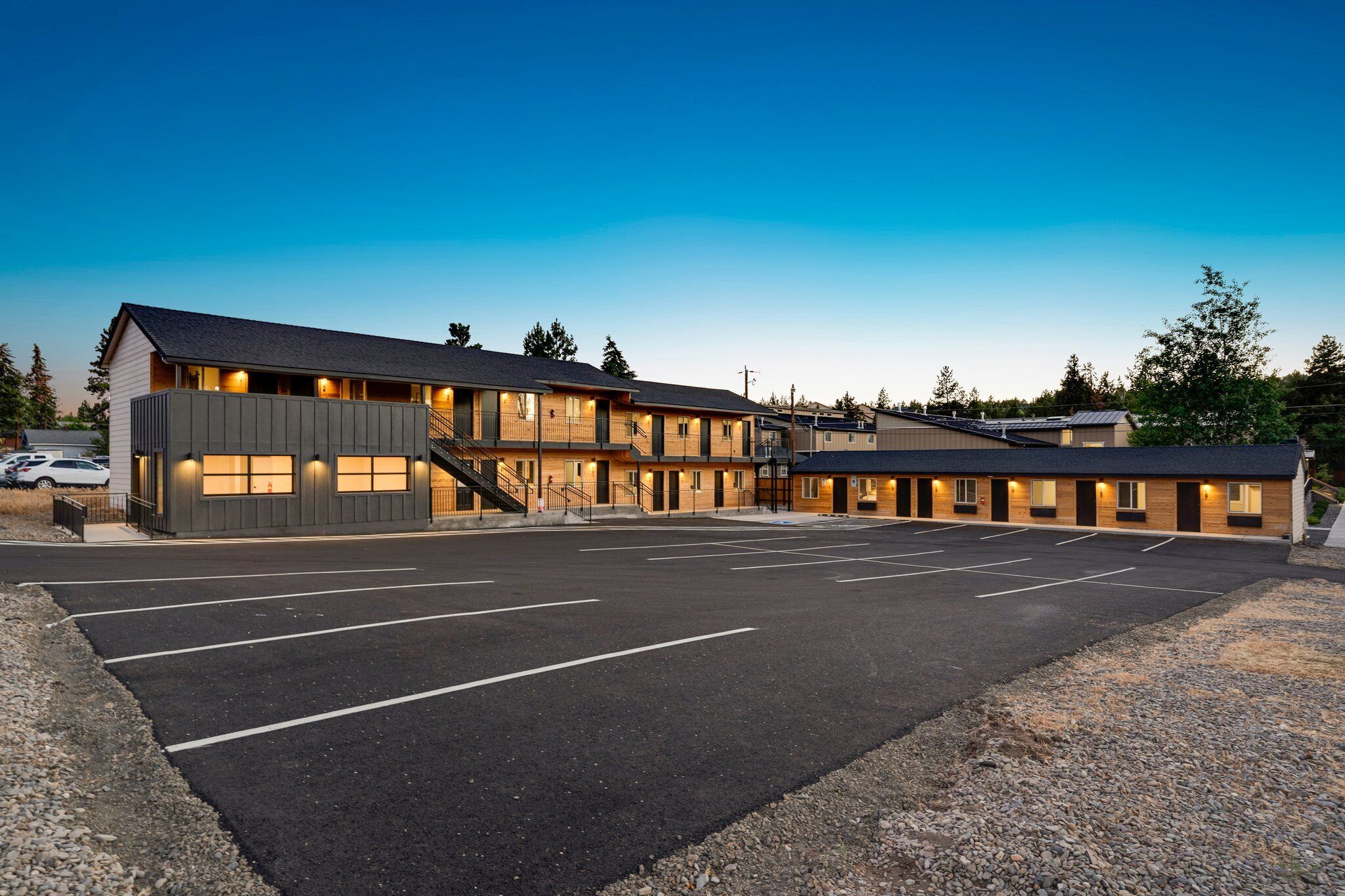 Ein Motel mit Parkplatz, mehreren Zimmern und einer Treppe, die in die obere Etage führt.