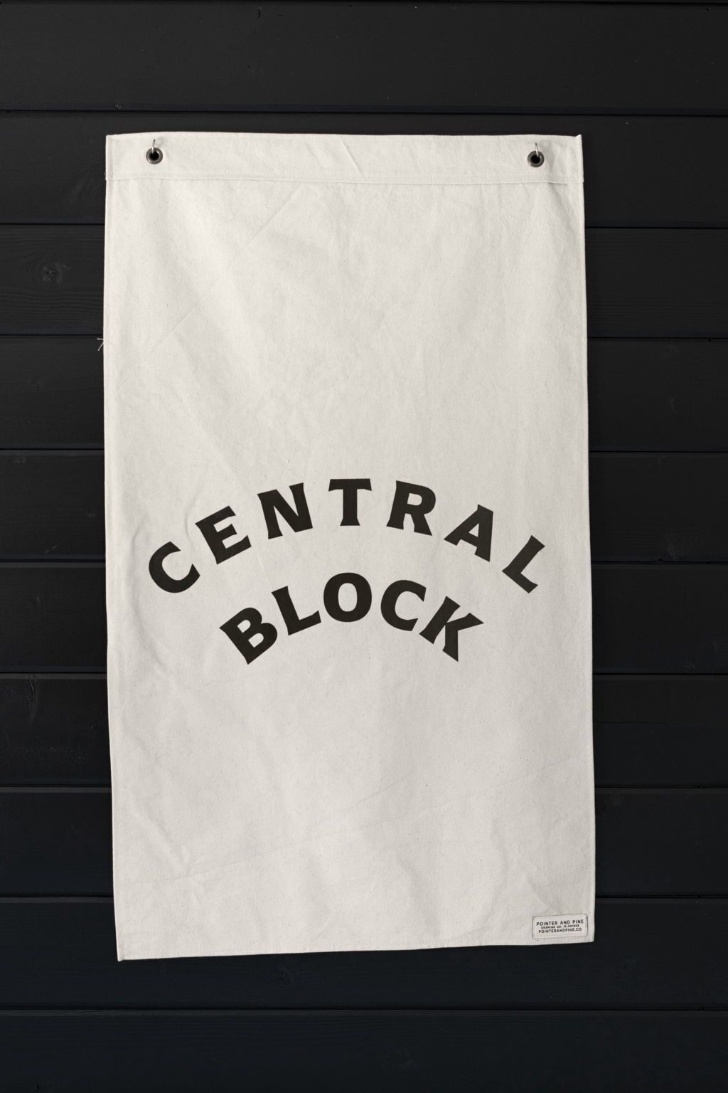 A white paper with 'CENTRAL BLOCK' printed on it, hanging on a black wooden wall.