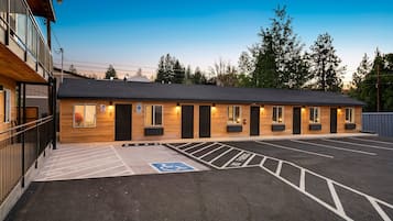 Un edificio con diverse porte e finestre, un parcheggio con posti delimitati e un'area accessibile in sedia a rotelle.