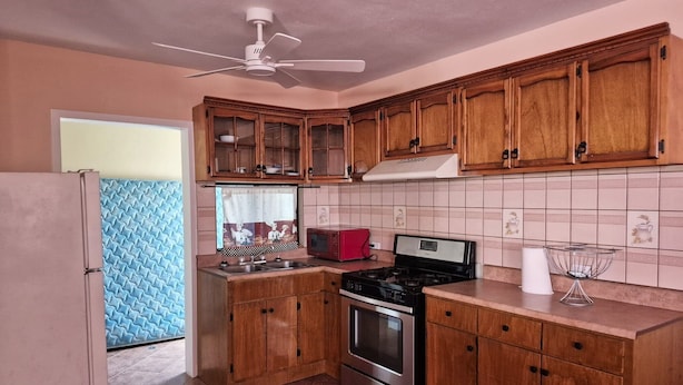 A kitchen with wooden cabinets, a stainless steel stove, a microwave, and a ceiling fan. - San Felipe Condo w/ Shared Pool & Beach Access - Rancho Bugambilias B (San Felipe)