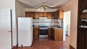 Uma cozinha com armários de madeira, geladeira branca, fogão e ventilador de teto.