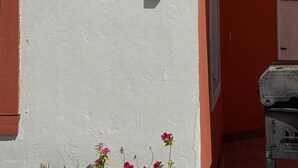 Fachada de edifício com parede branca e porta vermelha.