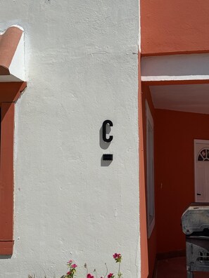 Eine Gebäudefassade mit weißer Wand und roter Tür.