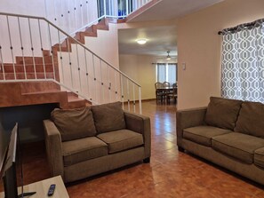 Ein Wohnzimmer mit zwei braunen Sofas, einem Fernseher und einer Treppe.