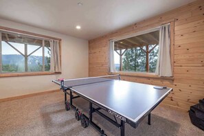 A ping pong table in a room with wooden walls and large windows. - Golden Oak Estate | 7BR Luxury. Wine Room. Views. (Big Bear Lake)