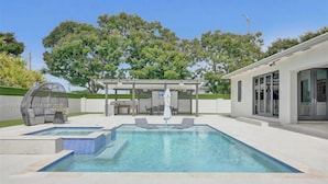 A modern outdoor pool area with a pergola, lounge chairs, and a covered seating area. - The Rainbow (Miami)