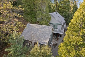 Ein zweistöckiges Haus mit Balkon, umgeben von dichtem Wald.