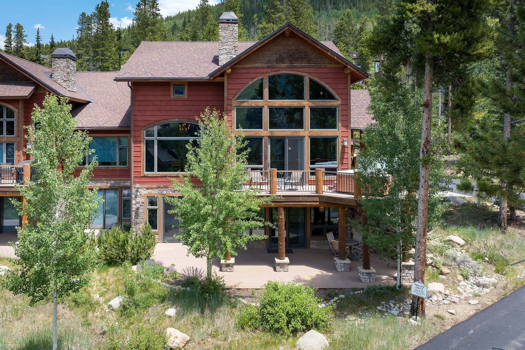 A large, multi-story house with a prominent balcony, stone chimney, and a well-maintained garden.