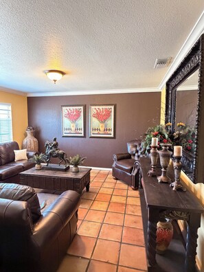 A living room with a brown sofa, a coffee table, a fireplace with decorative vases, and two framed floral paintings on the wall. - Beautiful family and pet friendly estate in Temecula Wine Country region (Aguanga)