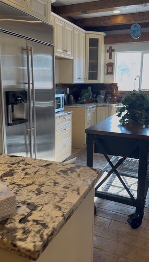 A kitchen with a granite countertop, stainless steel refrigerator, and wooden cabinets. - Beautiful family and pet friendly estate in Temecula Wine Country region (Aguanga)