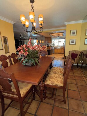 A dining area with a wooden table, chairs, a chandelier, and a vase of flowers. - Beautiful family and pet friendly estate in Temecula Wine Country region (Aguanga)