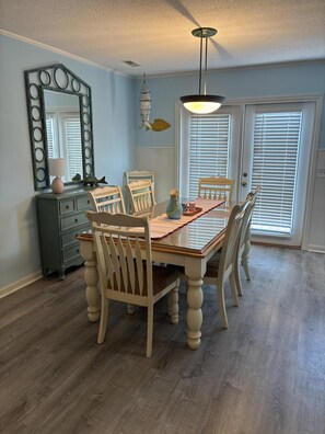 A dining room with a wooden table, six chairs, a dresser, a mirror, and a ceiling light fixture. - 3 Bedroom home with access to the canal! (Supply)